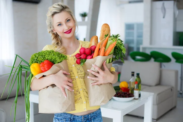 Gelukkig jonge huisvrouw met tassen vol met groenten — Stockfoto