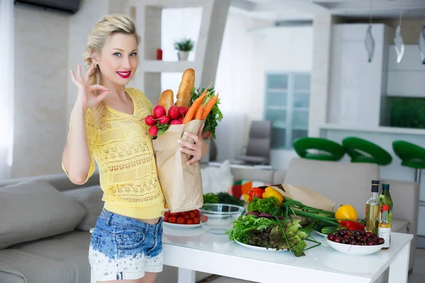 Happy young housewife with bags full of vegetables — Stock Photo, Image