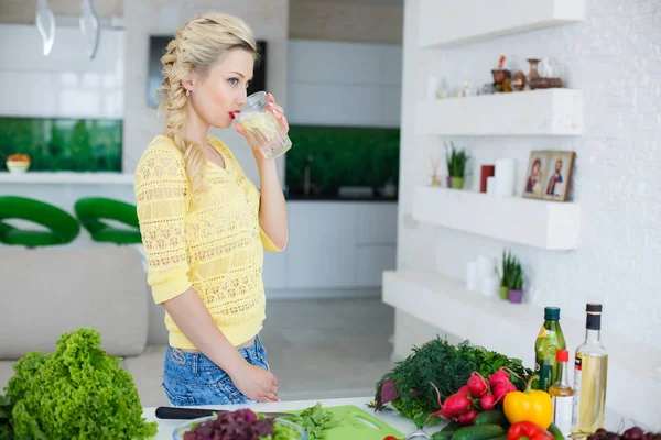 Portrait of a beautiful woman with a glass of water in the kitchen — Stock Photo, Image