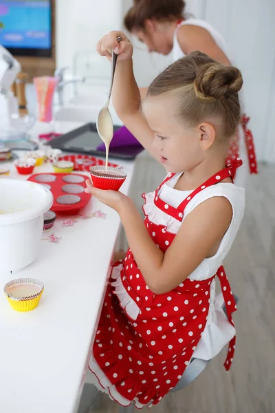 Mother and daughter cooking cupcakes into a large bright kitchen — Stock Photo, Image