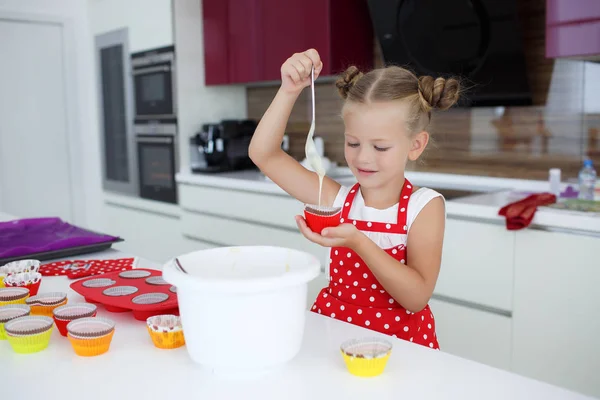 Pequeña ama de casa dedicada a hornear magdalenas en la cocina en casa —  Fotos de Stock