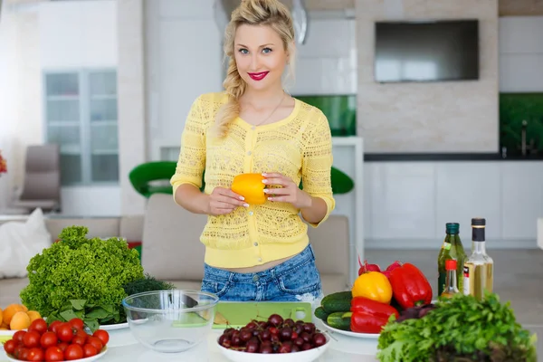 Jonge huisvrouw voorbereiding salade in de keuken — Stockfoto
