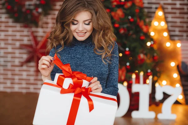 Meisje met de gift van Kerstmis in de buurt van mooie geklede kerstboom — Stockfoto