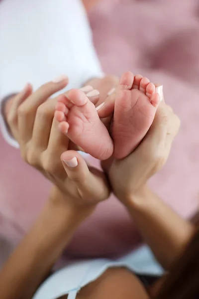 Närbild av baby fötter och mor händer — Stockfoto