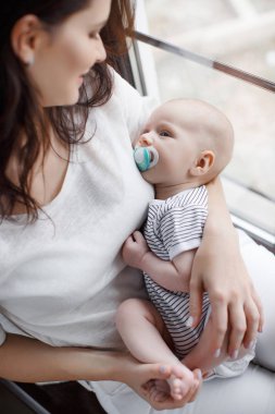 Yeni doğmuş çocuğunu tutan genç anne.