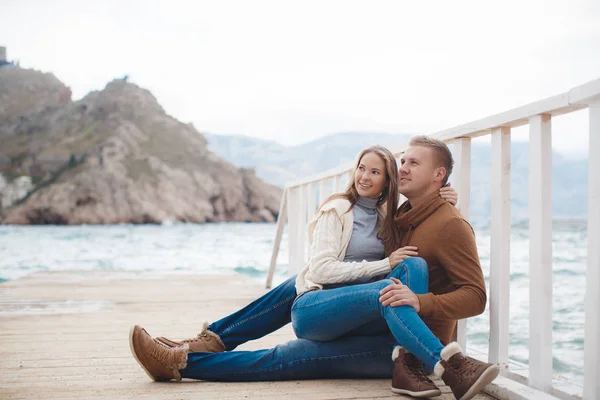 Couple on wooden pier near the sea in autumn — Stock Photo, Image