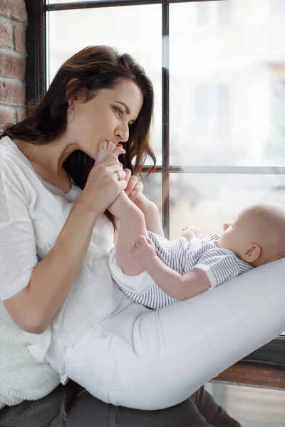 Happy mother kissing the feet of a newborn baby — Stock Photo, Image