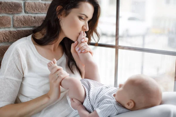 Happy mother kissing the feet of a newborn baby — Stock Photo, Image