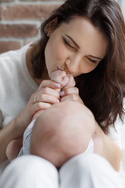 Happy mother kissing newborn baby handles — Stock Photo, Image