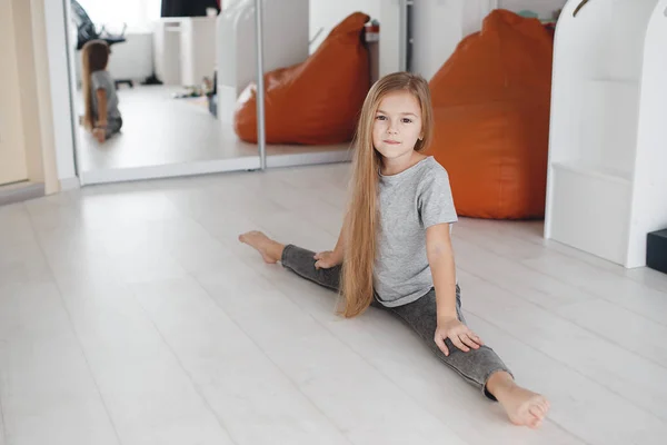 Petite belle fille gymnaste faire des exercices sur le sol à la maison — Photo