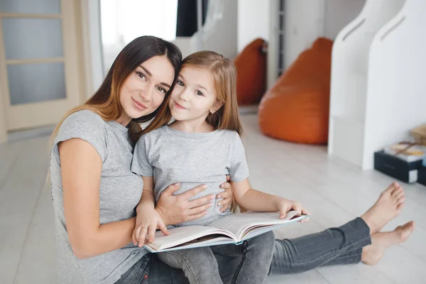 Anne ve kızı katta oturan bir kitap okuma — Stok fotoğraf