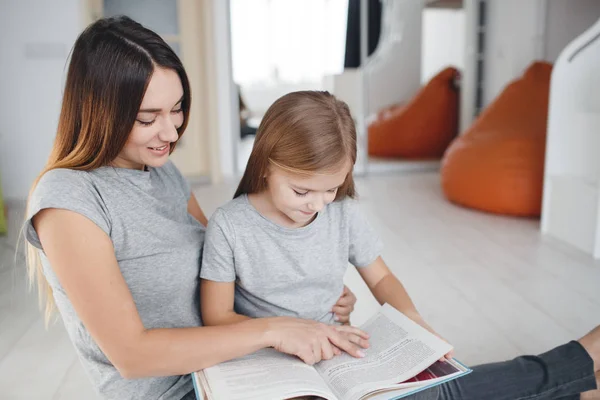 Mère et fille lisant un livre assis par terre — Photo