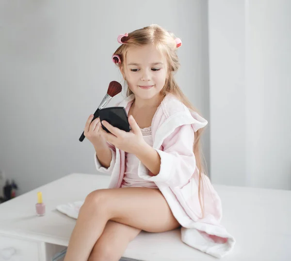 Маленькая девочка с зеркалом и кистью для макияжа — стоковое фото