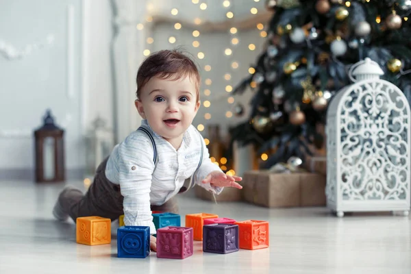 Schattige kleine jongen spelen in de buurt van de kerstboom met gekleurde blokjes — Stockfoto