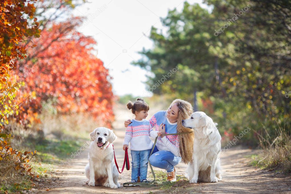 A young mother with a little girl and two dogs on a walk in the Park in autumn