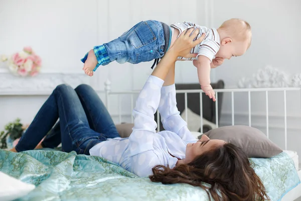 Mère heureuse jouant avec bébé garçon couché sur le lit à la maison — Photo