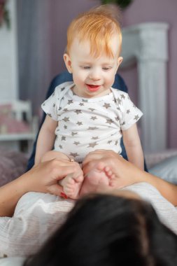 Mutlu anne evde yatakta yatarken erkek bebek ile oynarken