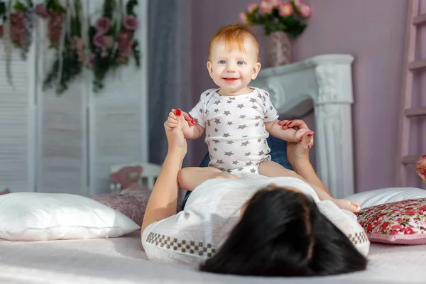 Mère heureuse jouant avec bébé garçon couché sur le lit à la maison — Photo