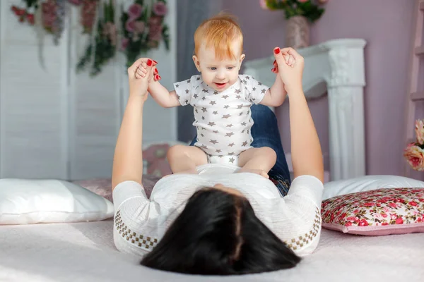 Happy mother playing with baby boy lying on bed at home — Stock Photo, Image
