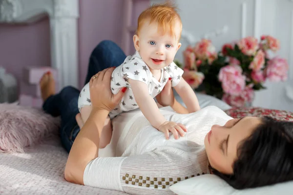 Mère heureuse jouant avec bébé garçon couché sur le lit à la maison — Photo