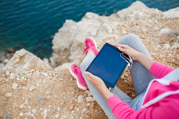 Kadın bir tablet bahar ile kayalık bir plajda — Stok fotoğraf