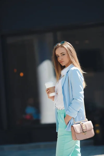 Young woman drinking coffee from paper cup on a city street