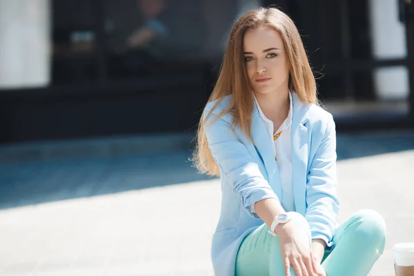 Портрет девушки в синем костюме, сидящей возле офиса — стоковое фото
