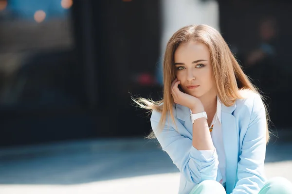 Портрет девушки в синем костюме, сидящей возле офиса — стоковое фото