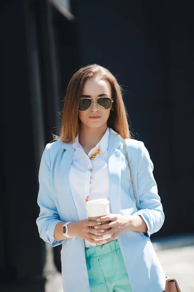 Jonge vrouw drinken koffie uit papier cup op een stad straat — Stockfoto