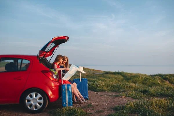 Two beautiful women are traveling on a red car — Stock Photo, Image