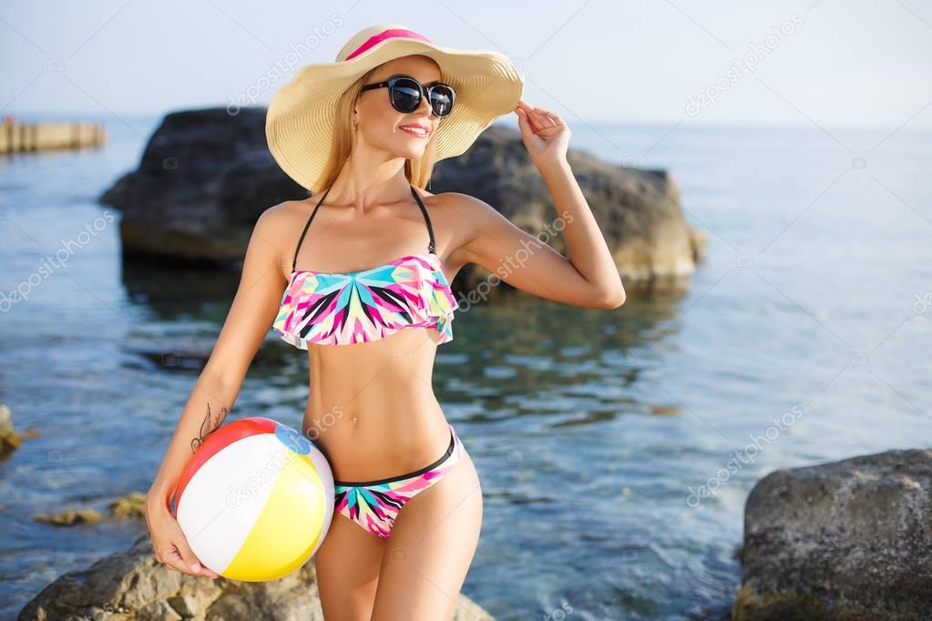 Beautiful slim woman in big hat on the beach