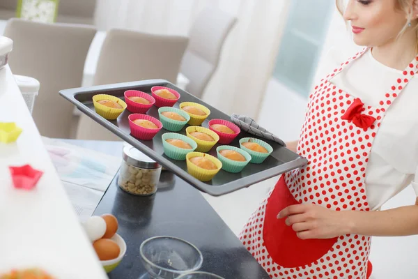 Souriant femme blonde cuisine cupcakes dans la cuisine — Photo