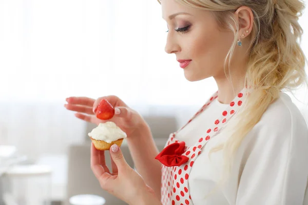 Smiling blonde woman cooking cupcakes in kitchen — Stock Photo, Image