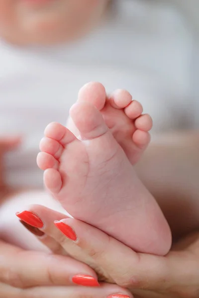 新生儿脚在母亲的手掌上 幸福的家庭 母亲和新生儿 身着白色长袍 温柔的双手 母亲轻轻地抱着婴儿的脚 孩子躺在一个慈爱的母亲的腿上 — 图库照片