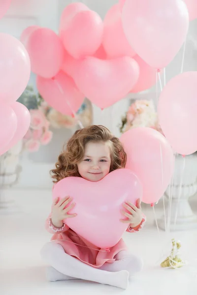 長い巻き毛 白タイツ 美しい笑顔とピンクのドレスに身を包んだ 歳の小さな女の子は たくさんのハートの形をしたピンクの風船と大きな明るい部屋で単独します バレンタインやお祝いパーティー — ストック写真