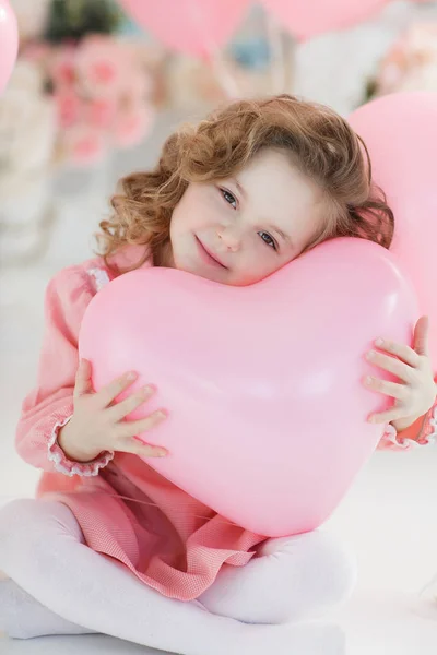 핑크색 드레스와 스타킹 미소와 년간의 소녀는 심장의 모양에 풍선의 제비를 — 스톡 사진