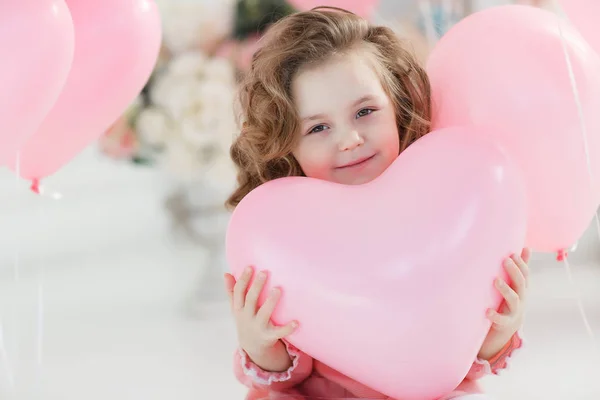 핑크색 드레스와 스타킹 미소와 년간의 소녀는 심장의 모양에 풍선의 제비를 — 스톡 사진