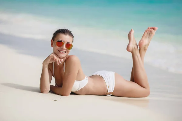 Beautiful woman on white sand near the ocean.Woman swim and relax in the sea. Happy island lifestyle. White sand, crystal-blue sea of tropical beach. Vacation at Paradise. Ocean beach relax, travel to Maldives islands