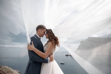 Güzel gelin ve damat onların düğün günü denize yakın kayalık bir kıyısında yürümek. Plaj, balayı, mutlu gülümseyen adam ve kadın yürüyüş deniz deniz okyanus tatil Travel.Happy düğün günü Genç Çift.