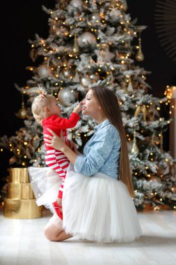Aile Noel 'i kutlar. Sihirli gecede kızı olan mutlu bir anne. Hediyeler, arka planda sarı ışıklar olan Noel ağacı. Mutlu Noeller. Şefkat, şefkat ve karşılıklı anlayış. Noel ve yeni yıl tatilleri aile çevresinde..