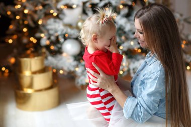 Aile Noel 'i kutlar. Sihirli gecede kızı olan mutlu bir anne. Hediyeler, arka planda sarı ışıklar olan Noel ağacı. Mutlu Noeller. Şefkat, şefkat ve karşılıklı anlayış. Noel ve yeni yıl tatilleri aile çevresinde..
