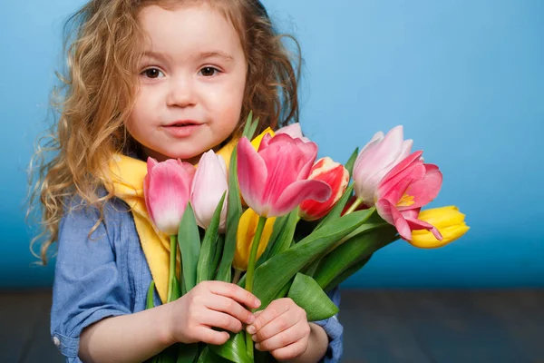 スタジオの明るい緑の背景に隔離された贈り物として 多色のチューリップの花束を保持している赤い巻き毛を持つ笑顔の小さな女の子の春の肖像画 — ストック写真
