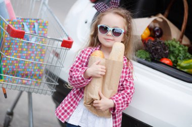 Tramvayı olan sevimli bir bebek marketten taze sebze seçiyor. Bir marketin yanındaki otoparkta büyük bir market arabası olan kız. Büyük bir tramvayı olan küçük bir kız büyük bir süpermarketten taze yiyecek ve sebze alır.