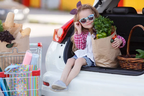 可爱的婴孩与推车选择新鲜蔬菜在当地商店 在商店附近的停车场里有一辆大购物车的女孩 一个拿着大推车的小女孩在一个大超市里买新鲜的食物和蔬菜 — 图库照片