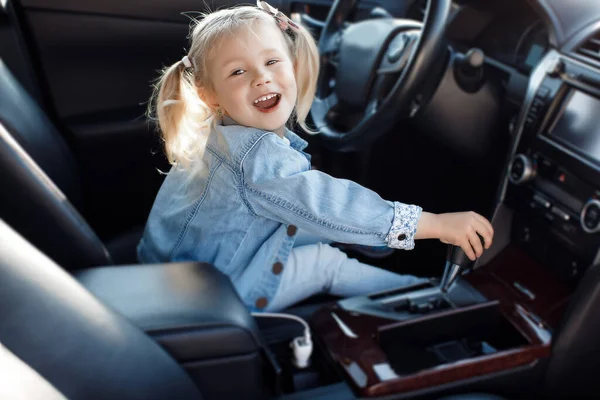 一个小女孩坐在车里司机的座位上 — 图库照片