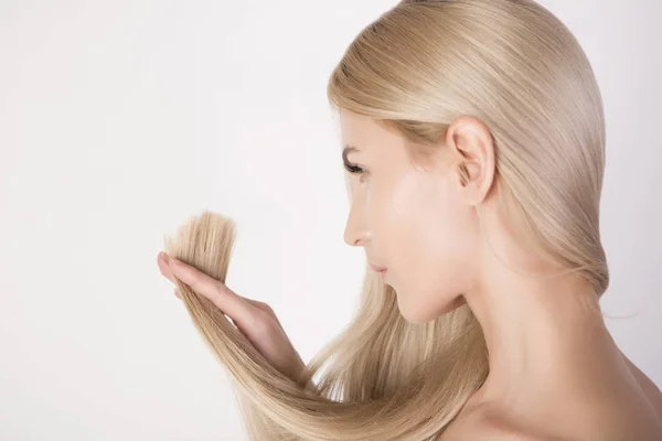 Piękna kobieta, patrząc na jej końcach zdrowe włosy i nową fryzurę — Zdjęcie stockowe