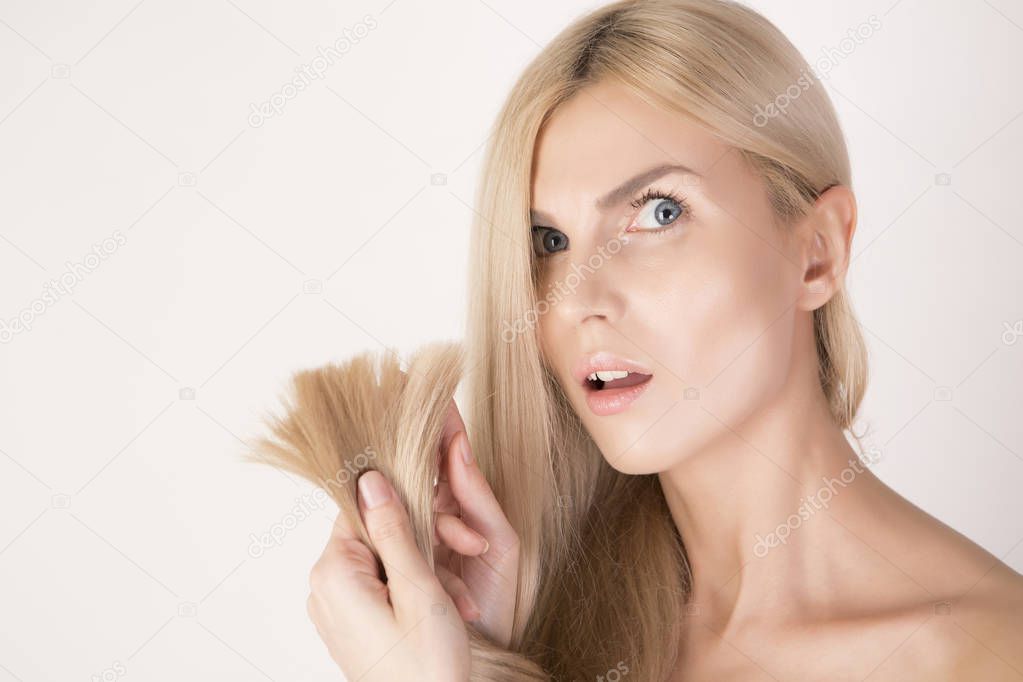 Unhappy woman pointing on her hair ends. Beauty care.