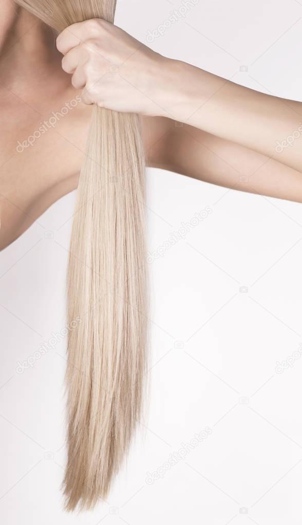 Healthy platinum blonde hair in a tale. Girl holding her hair in