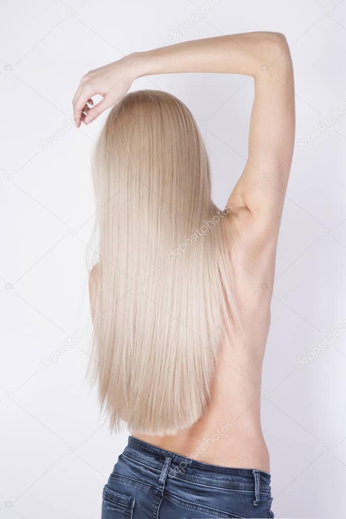 Skinny model with perfect long blonde hair posing in a studio.