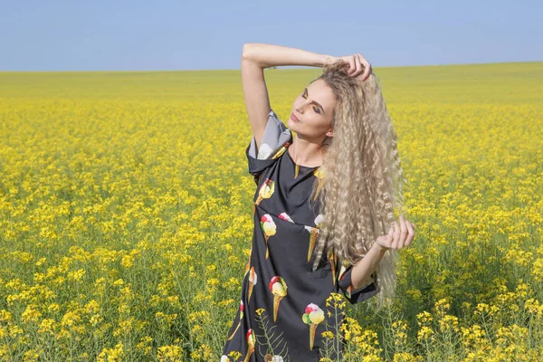 Young woman with long curly blonde hair in a field. — Stock Photo, Image